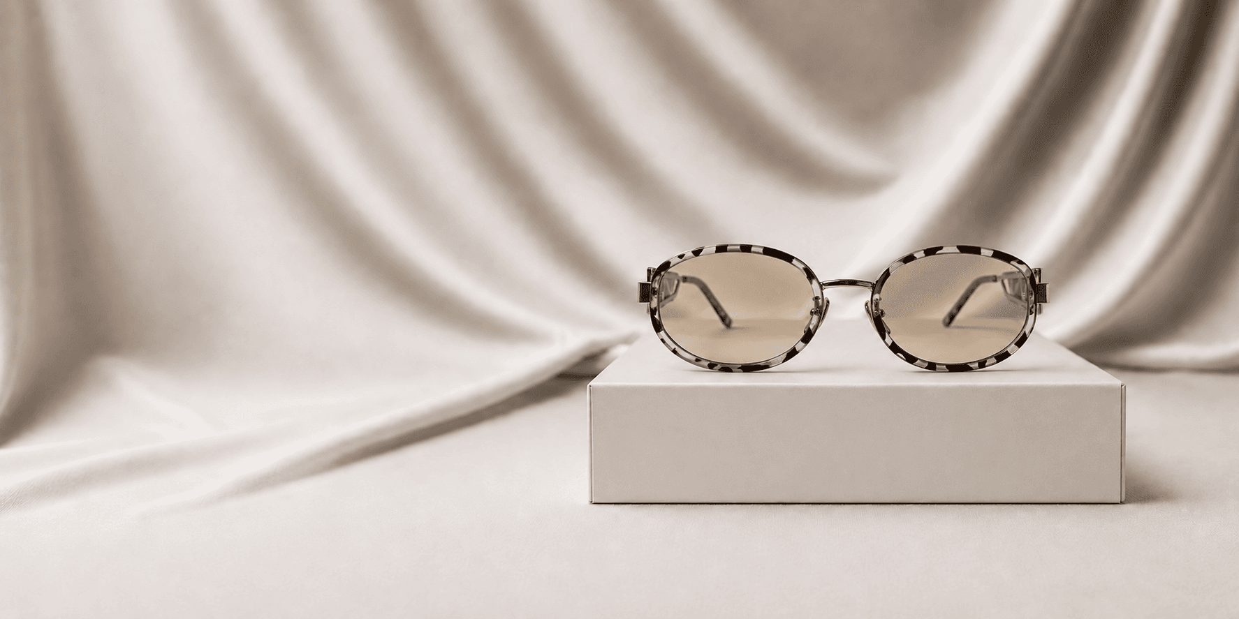 Lunettes de soleil écaille Lumaura posées sur un écrin, tissu drapé en fond
